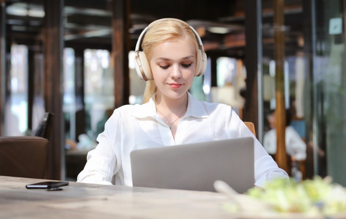 A woman wearing edifier w830bt headphone, watching the laptop