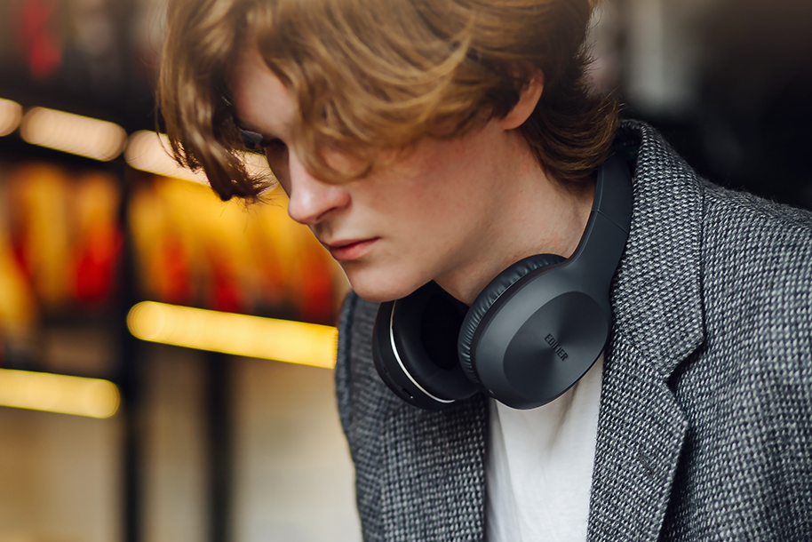 A boy with black edifier headphones around his neck
