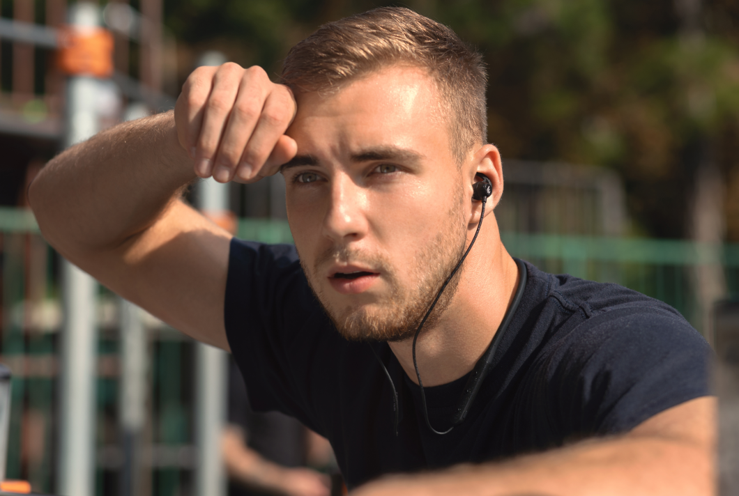 A man is wiping sweat, wearing EDIFIER sports headphones