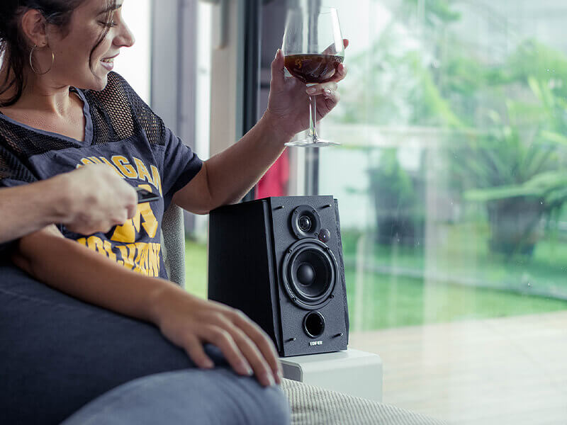 A woman holding the wine, with edifier speaker besids