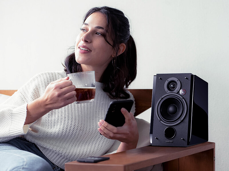 The woman drinking tea with edifier speaker besides