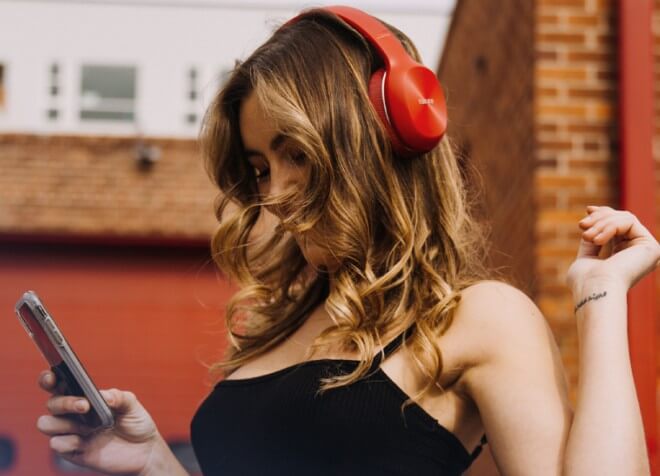 A woman wearing red headphones, watching phone